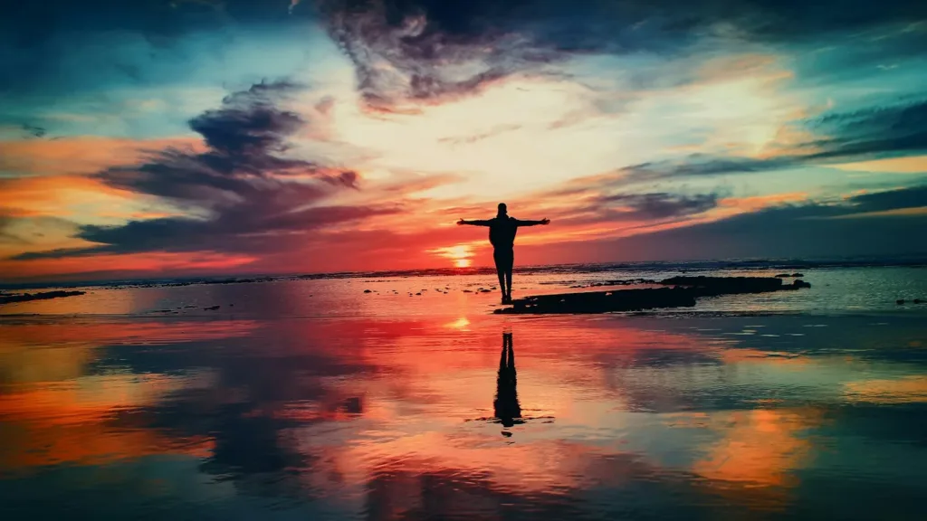 silhouette-person-standing-on-rock-surrounded-by-water