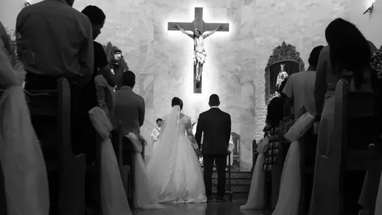 A-couple-getting-married-in-a-church-with-guests-and-a-crucifix
